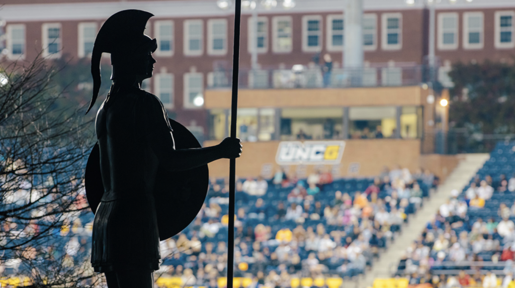 Spartan statue facing over full crowd at UNCG stadium